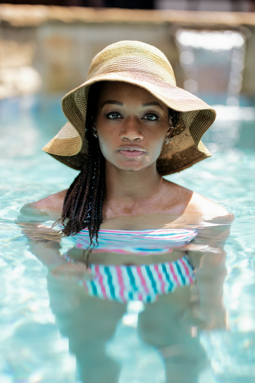 woman in brown sun hat and bikini in pool