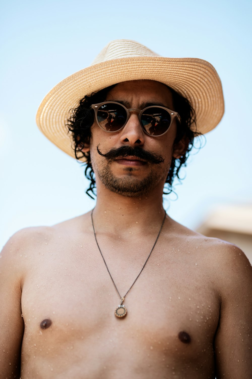 topless man wearing beige hat and black sunglasses