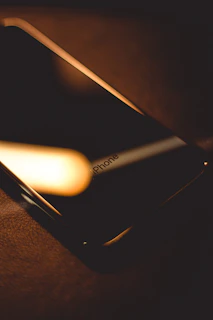 Close-up of a sleek iPhone resting on a silver surface with soft shadows.
