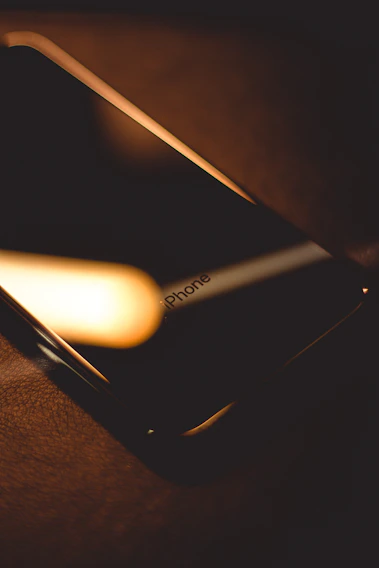 Close-up of a sleek iPhone resting on a silver surface with soft shadows.