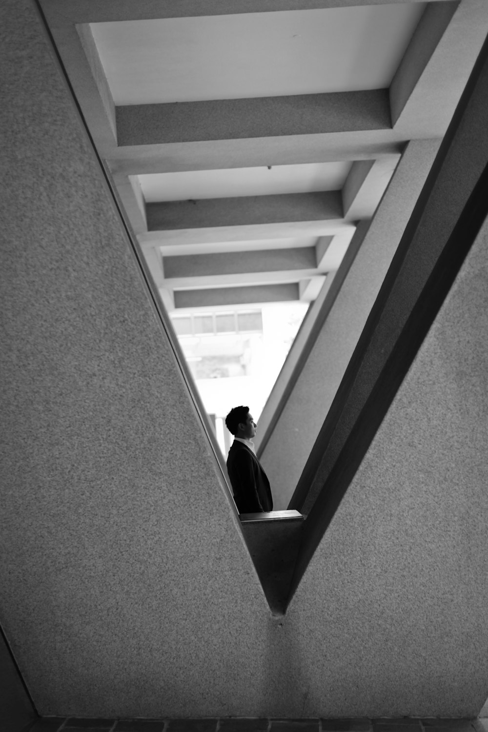 grayscale photography of man standing near building