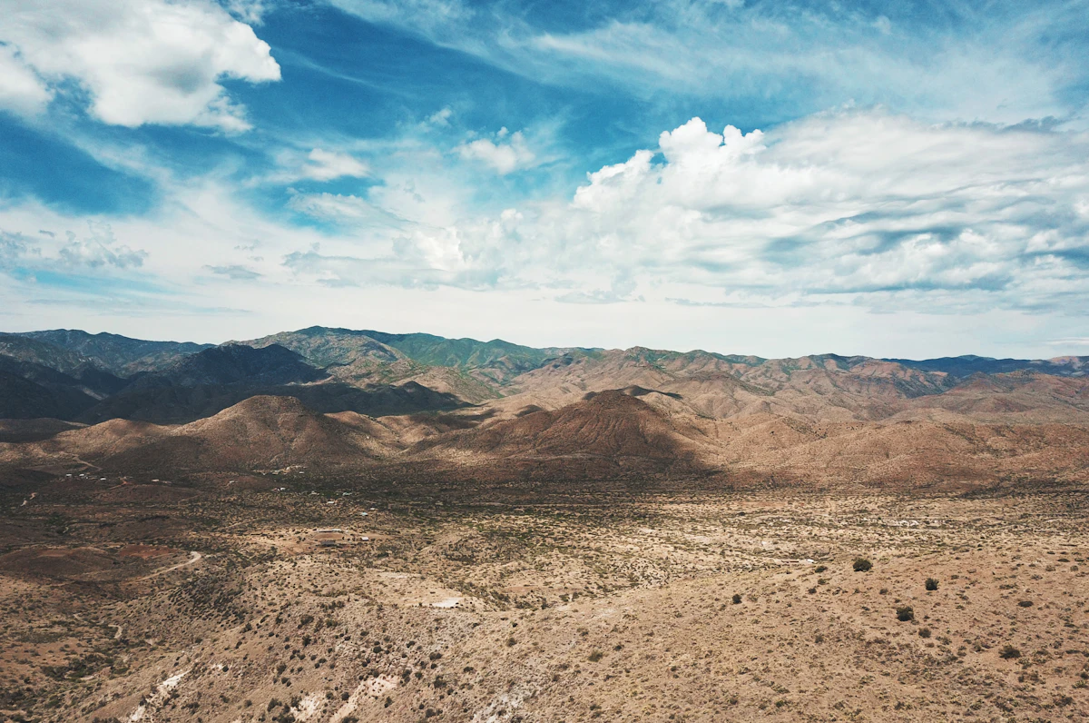 An aerial view of bare desert hills and ridges off Antelope Creek Road near Mayer, Arizona, under big clouds