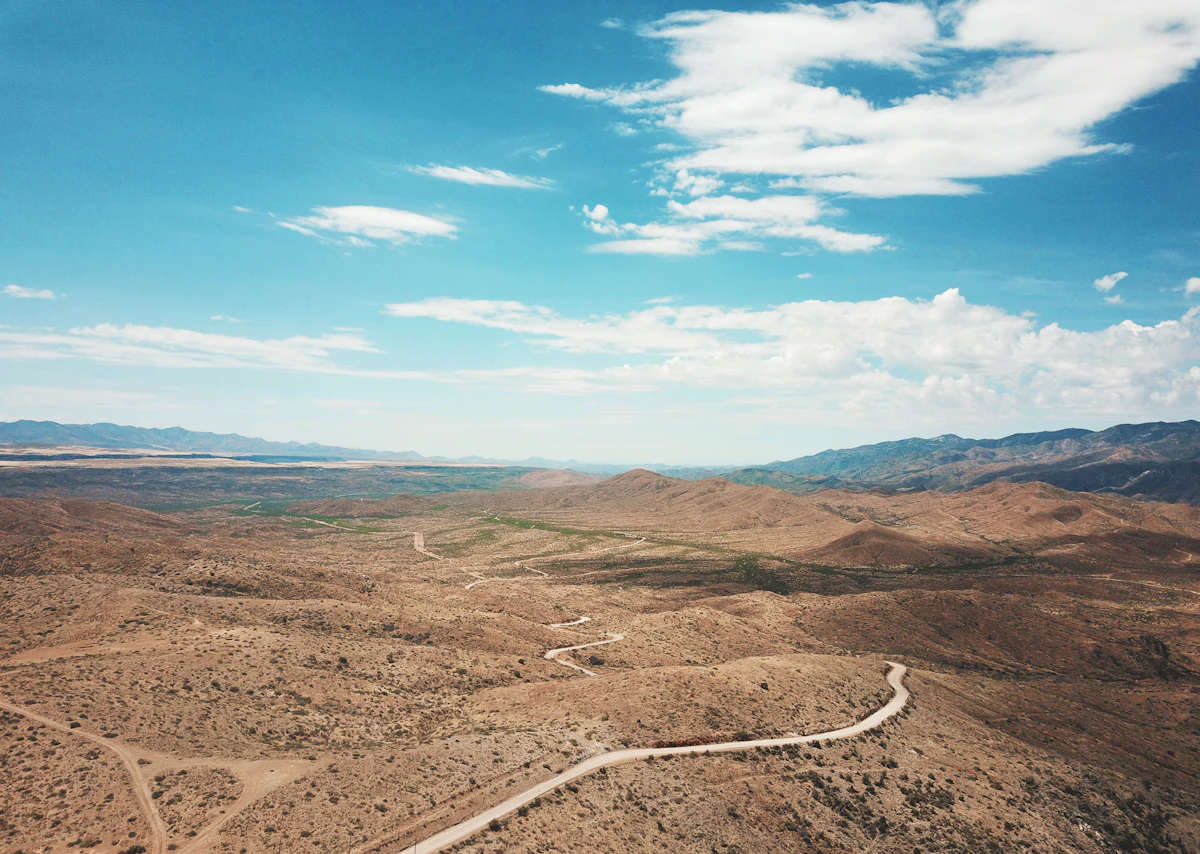 An aerial view of a dirt road winding over desert hills near Mayer, Arizona, with mountains on the horizon