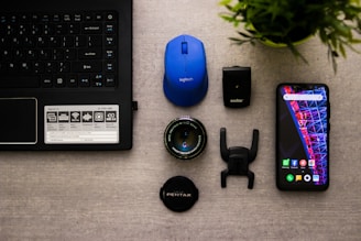 laptop, blue computer mouse, smartphone, and camera lens