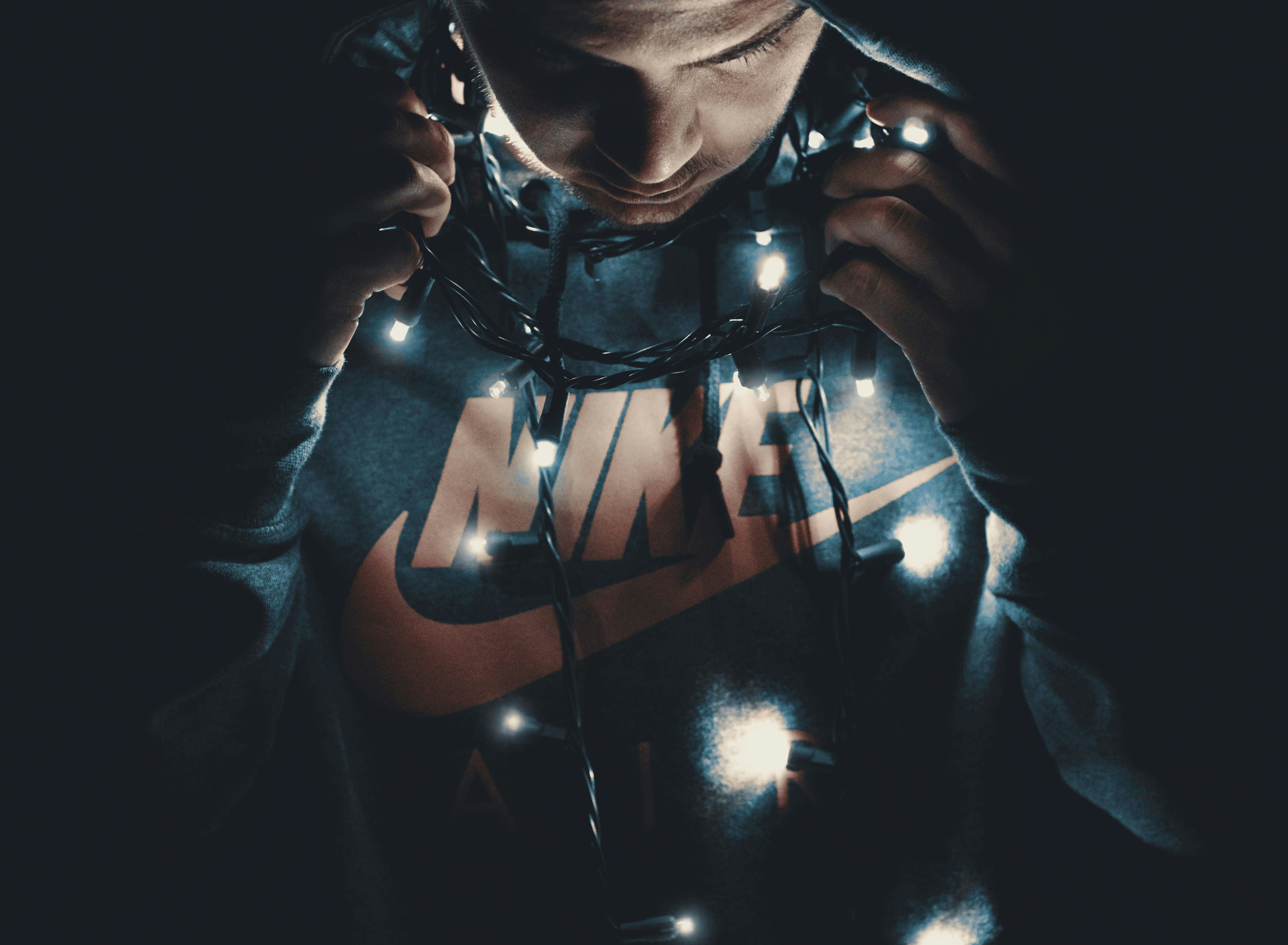 Man in Nike hoodie sweatshirt with string lights