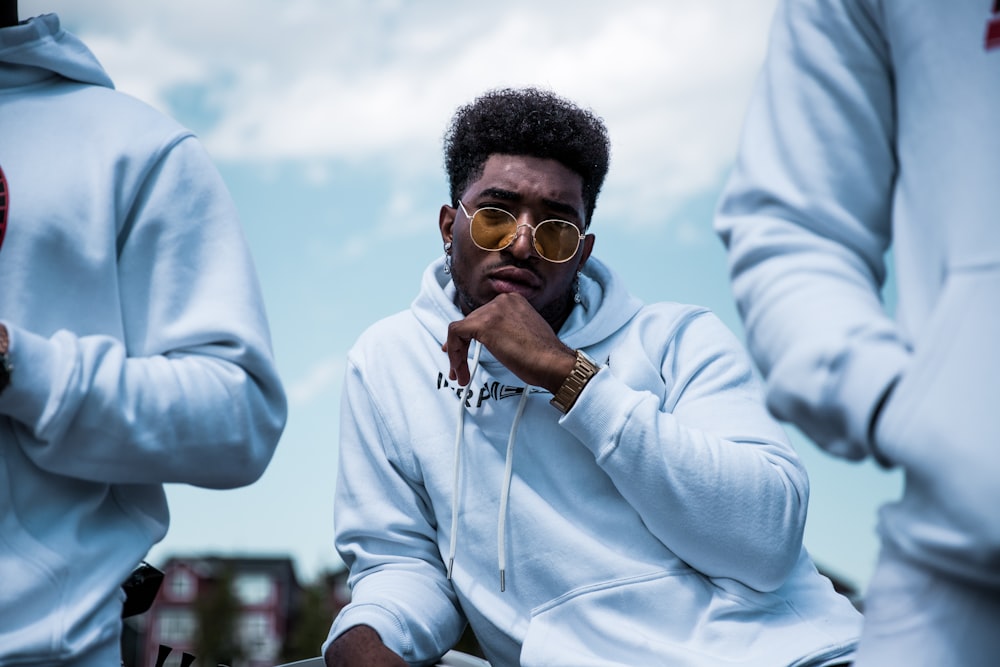 Photo de mise au point superficielle d’un homme en pull à capuche blanc portant des lunettes de soleil brunes