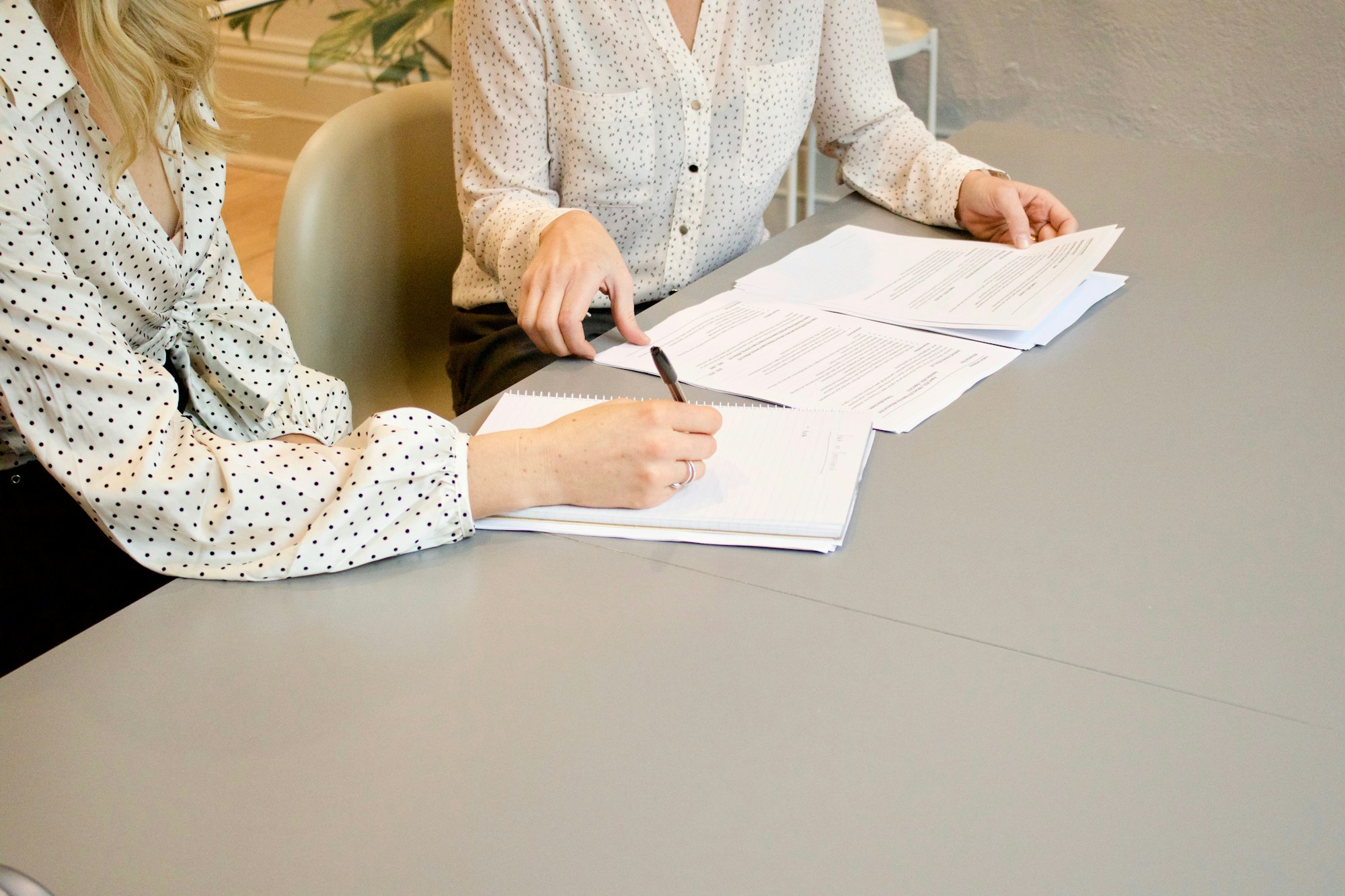 Two managers review resumes while taking notes.