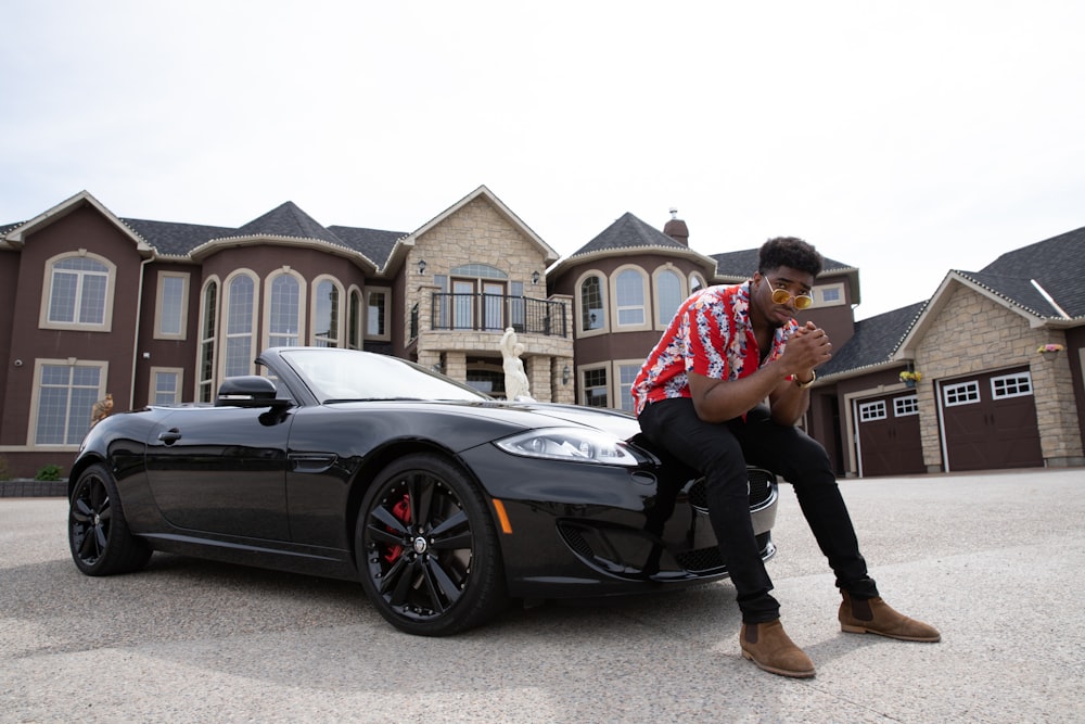 man sitting on black convertible coupe