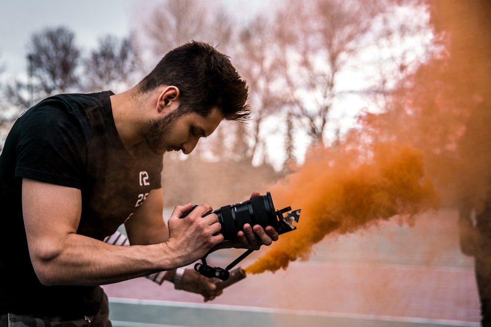 man in black T-shirt holding DSLR camera