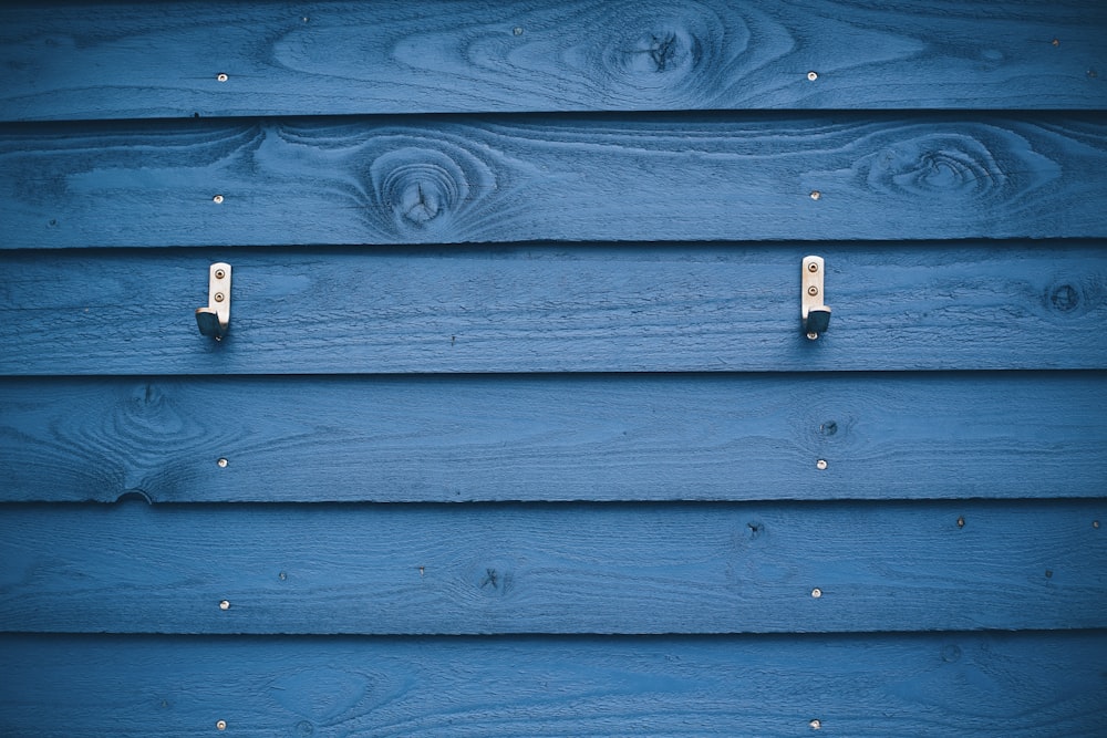 Gancho de metal gris sobre tablón de madera azul
