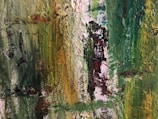 An abstract painting with thick brush strokes and a textured surface. The artwork features a blend of vibrant greens and yellows, with hints of red and black interspersed through the composition. The texture and colors create an impression of natural elements or foliage.