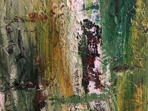 An abstract painting with thick brush strokes and a textured surface. The artwork features a blend of vibrant greens and yellows, with hints of red and black interspersed through the composition. The texture and colors create an impression of natural elements or foliage.