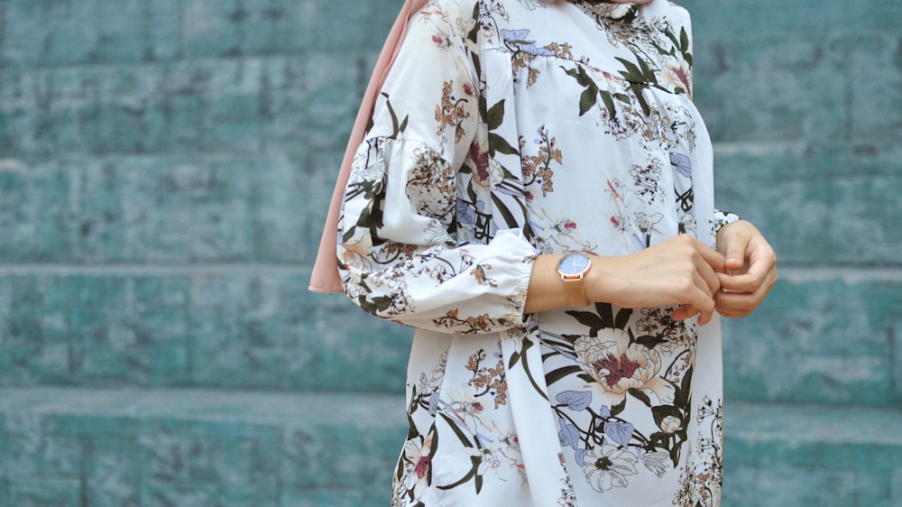 a woman in a floral print dress holding a pink purse