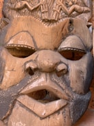 Close-up of a hand-carved wooden mask with intricate details and warm tones.