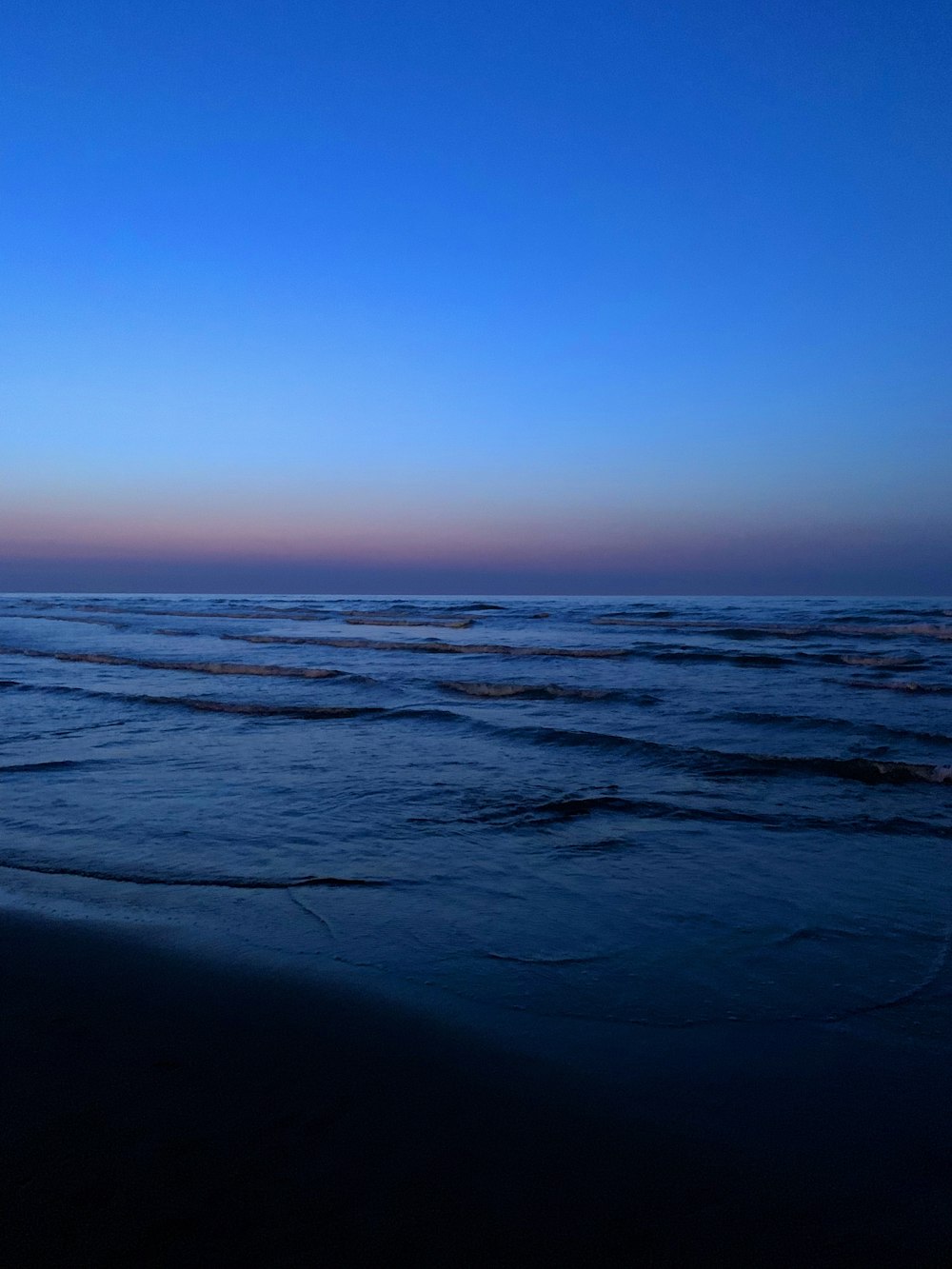 una persona che cammina sulla spiaggia al tramonto