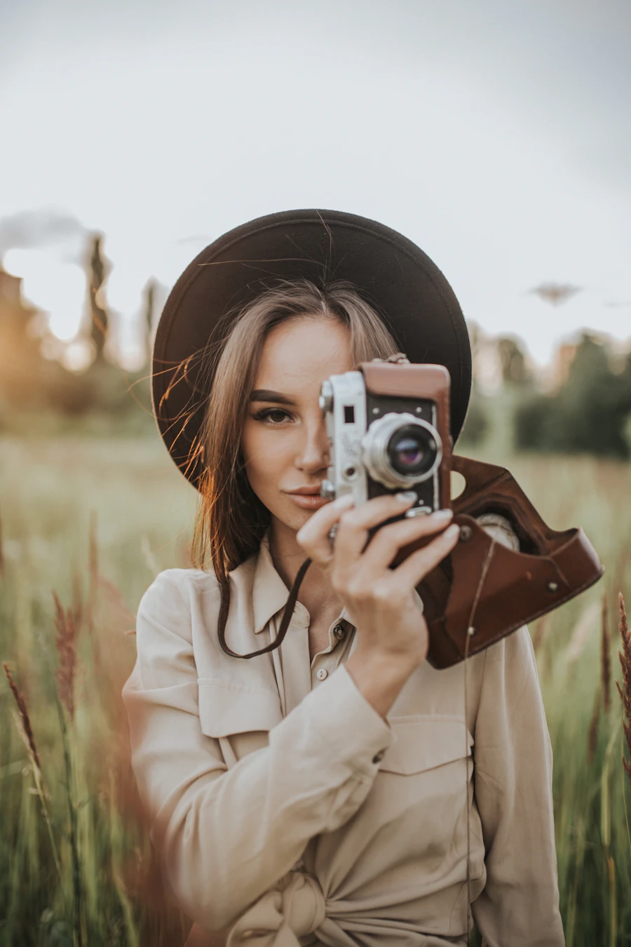A photographer holding her camera while standing in an open field
