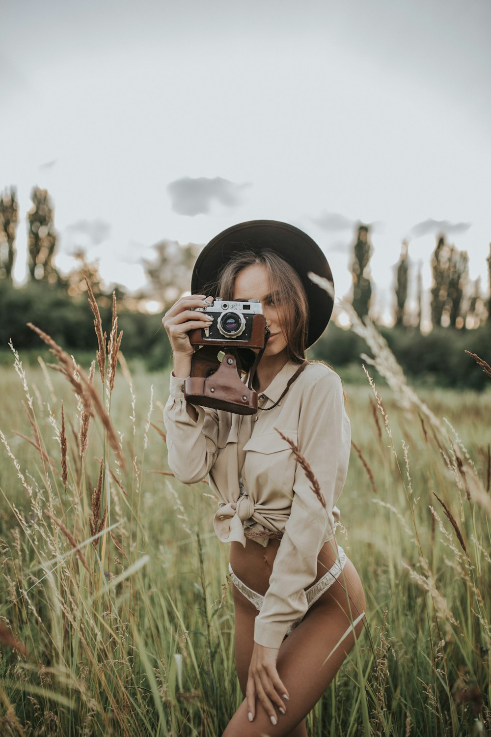 woman wearing white pantie holding gray and brown camera