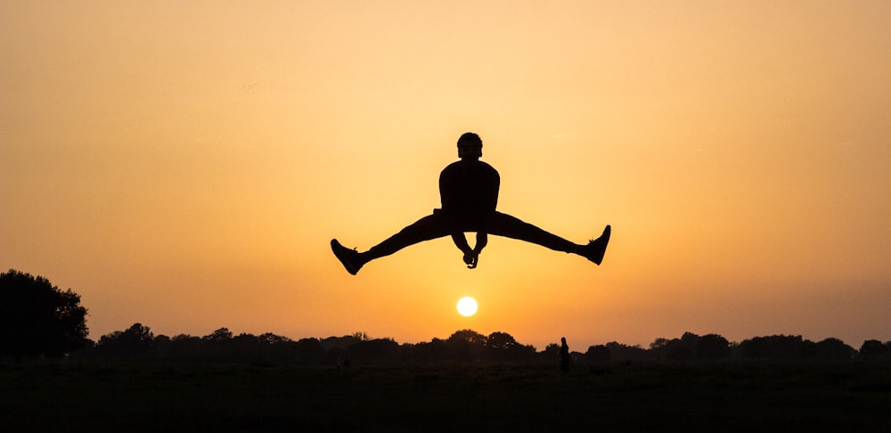uma pessoa pulando no ar ao pôr do sol