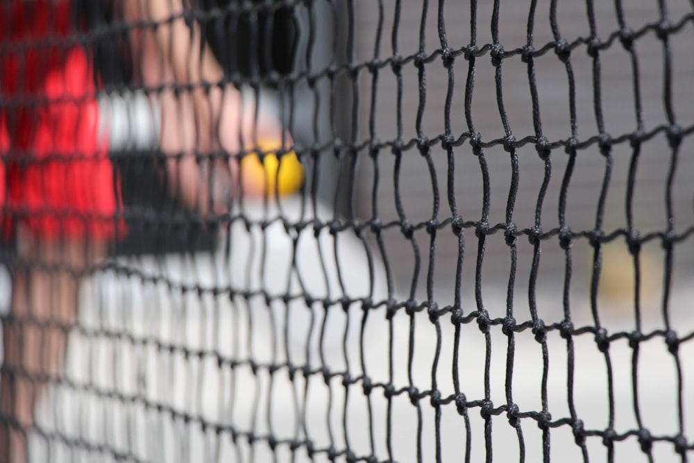a close up of a tennis net with a person in the background