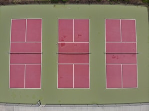 Vue large et lumineuse des 12 courts intérieurs de pickleball, disposés en quatre rangées de trois.