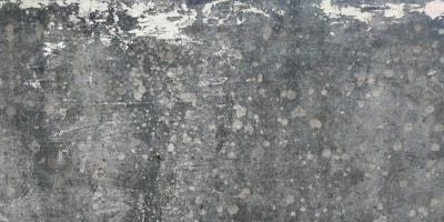 Weathered and textured concrete surface with patches of discoloration, giving a rustic and distressed appearance.