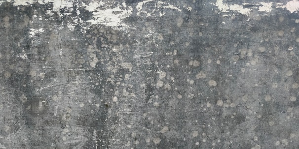 Weathered and textured concrete surface with patches of discoloration, giving a rustic and distressed appearance.