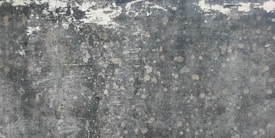 Weathered and textured concrete surface with patches of discoloration, giving a rustic and distressed appearance.