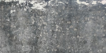 Weathered and textured concrete surface with patches of discoloration, giving a rustic and distressed appearance.