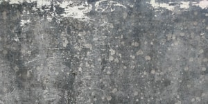 Weathered and textured concrete surface with patches of discoloration, giving a rustic and distressed appearance.