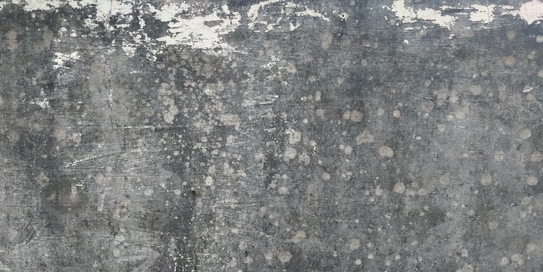 Weathered and textured concrete surface with patches of discoloration, giving a rustic and distressed appearance.