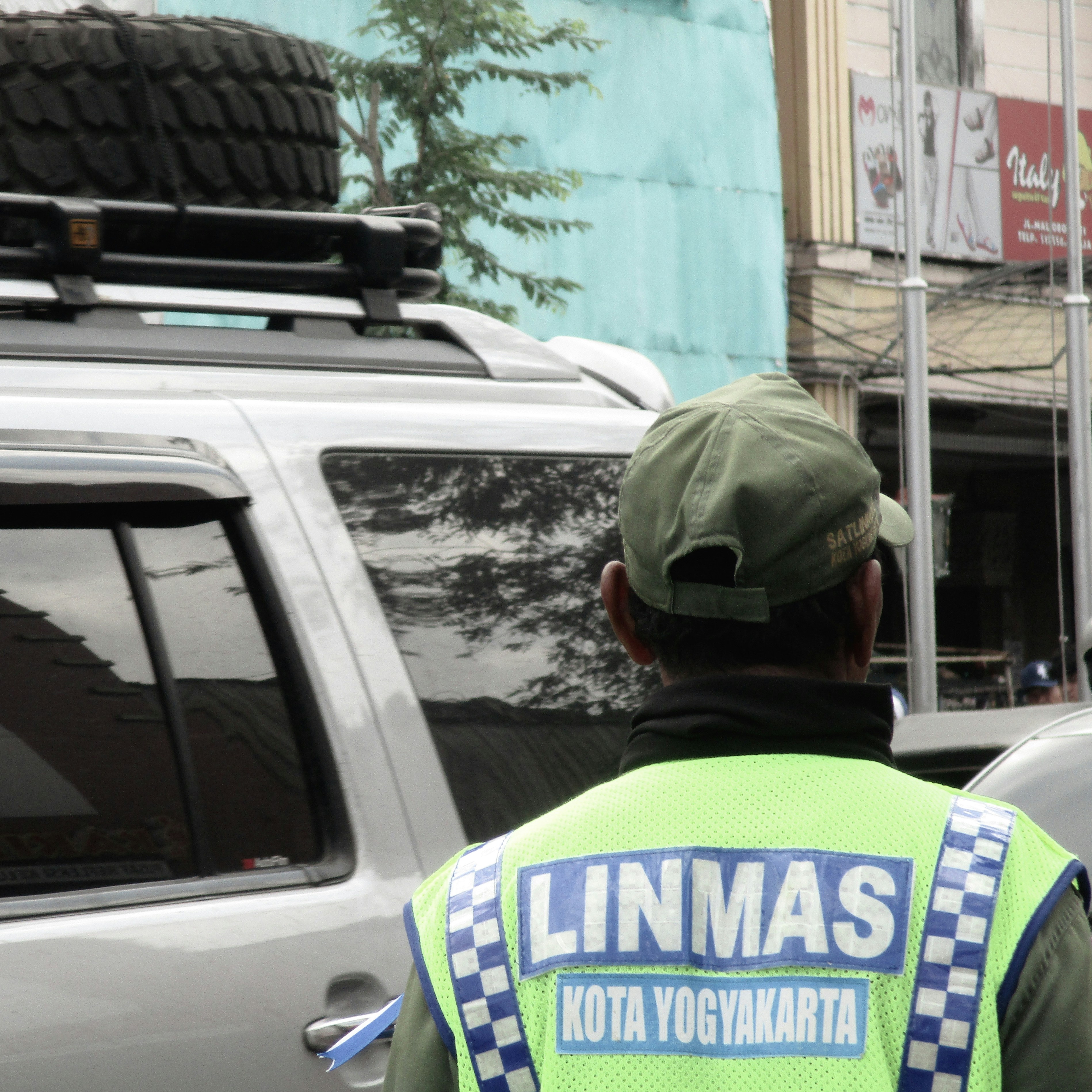 Roadside assistance technician in safety vest helping driver with flat tire replacement on highway shoulder