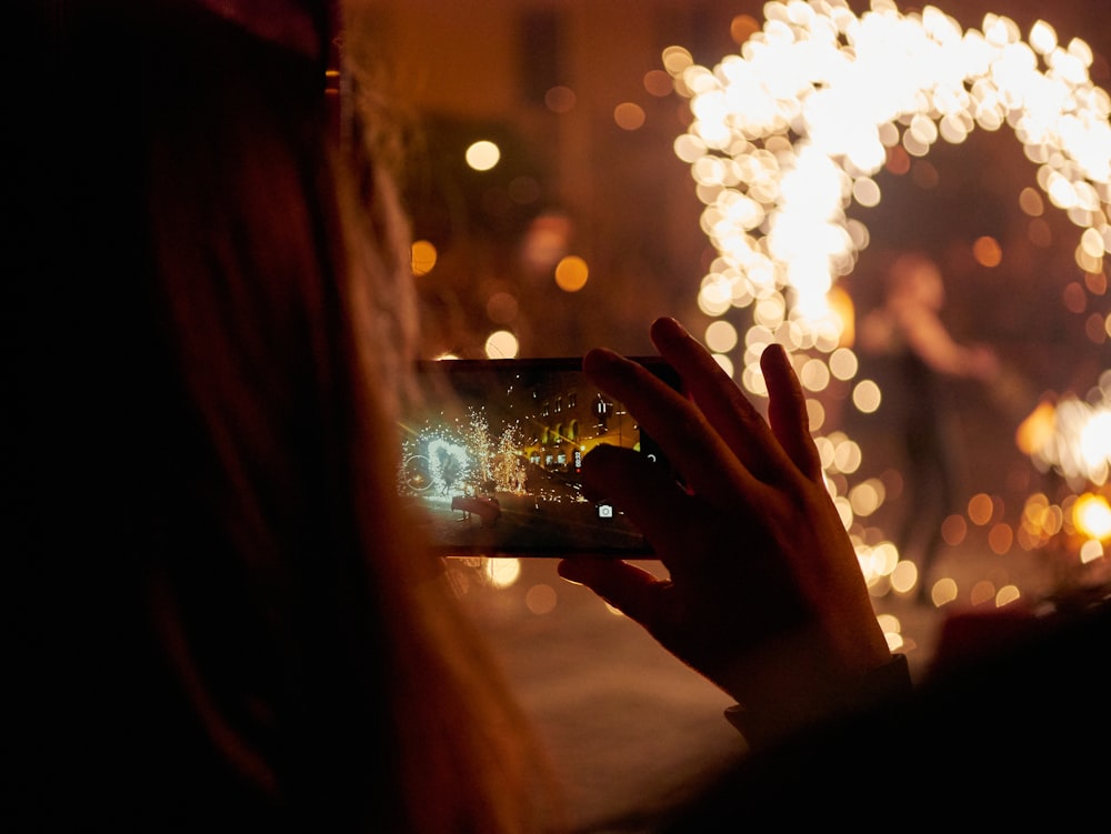 woman taking photo near string lights