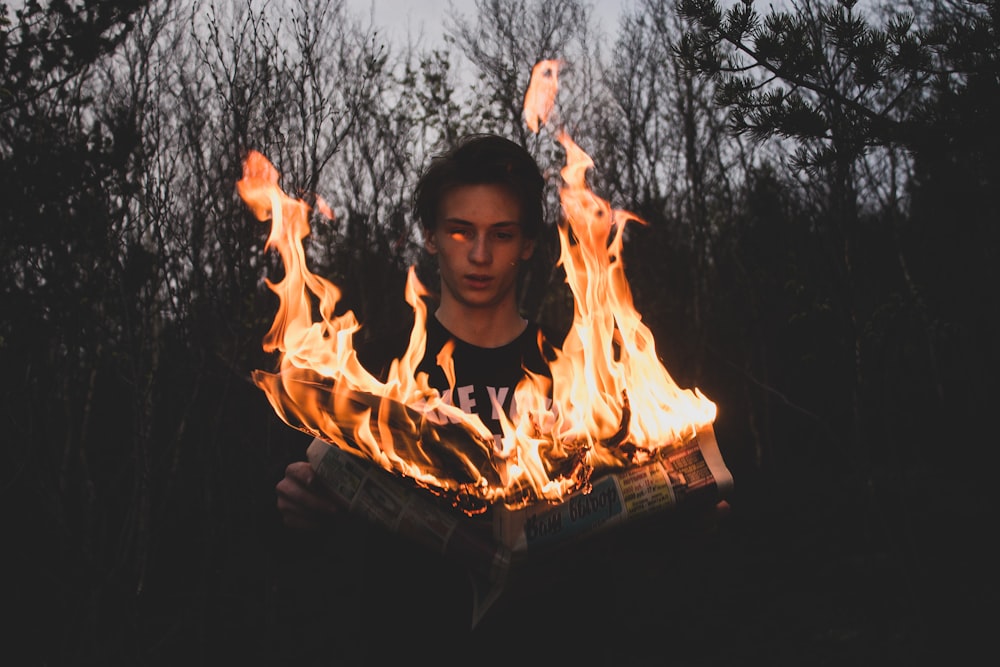 man holding flaming newspaper