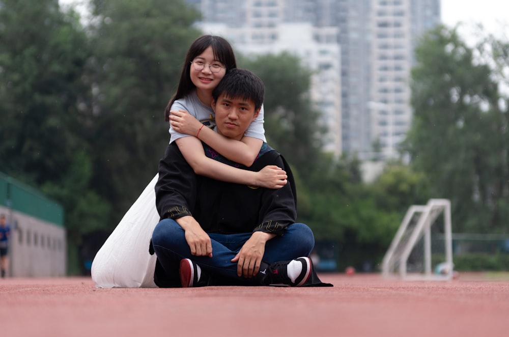 woman back hugging man squatting on field