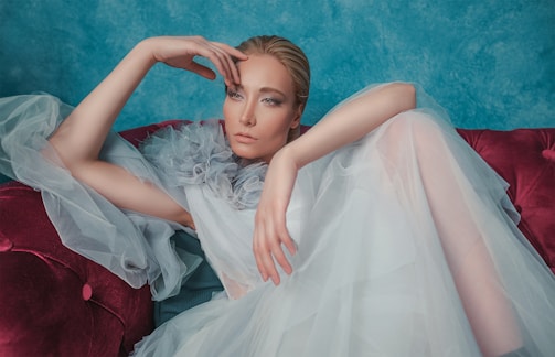 woman in white dress sitting on red sofa