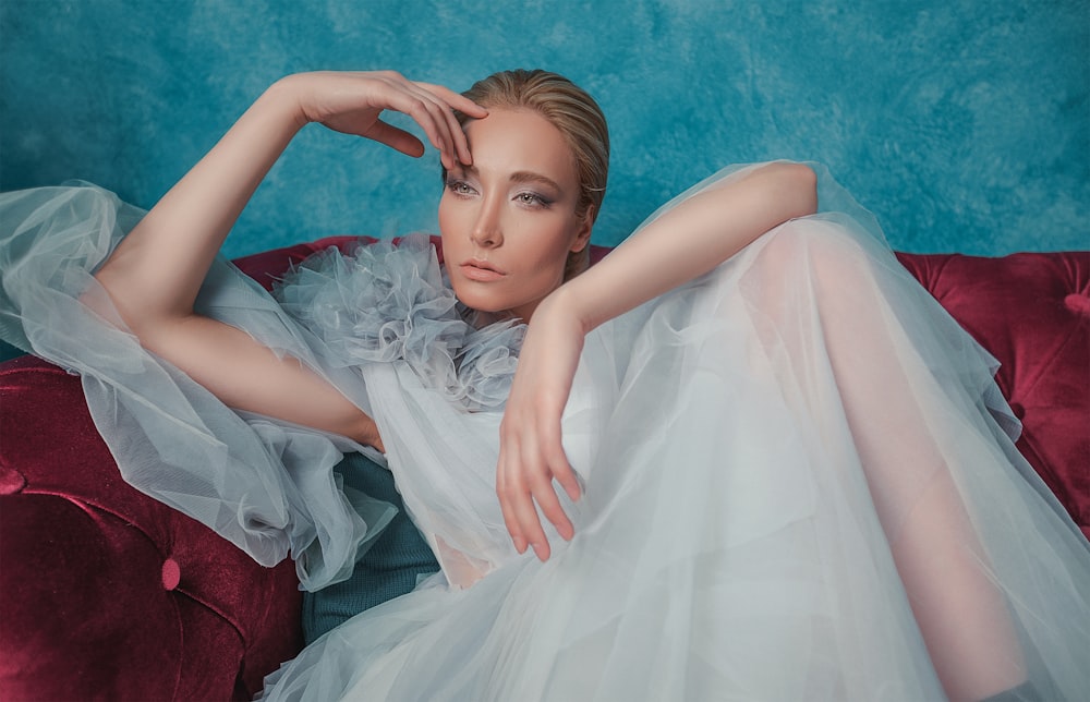 woman in white dress sitting on red sofa