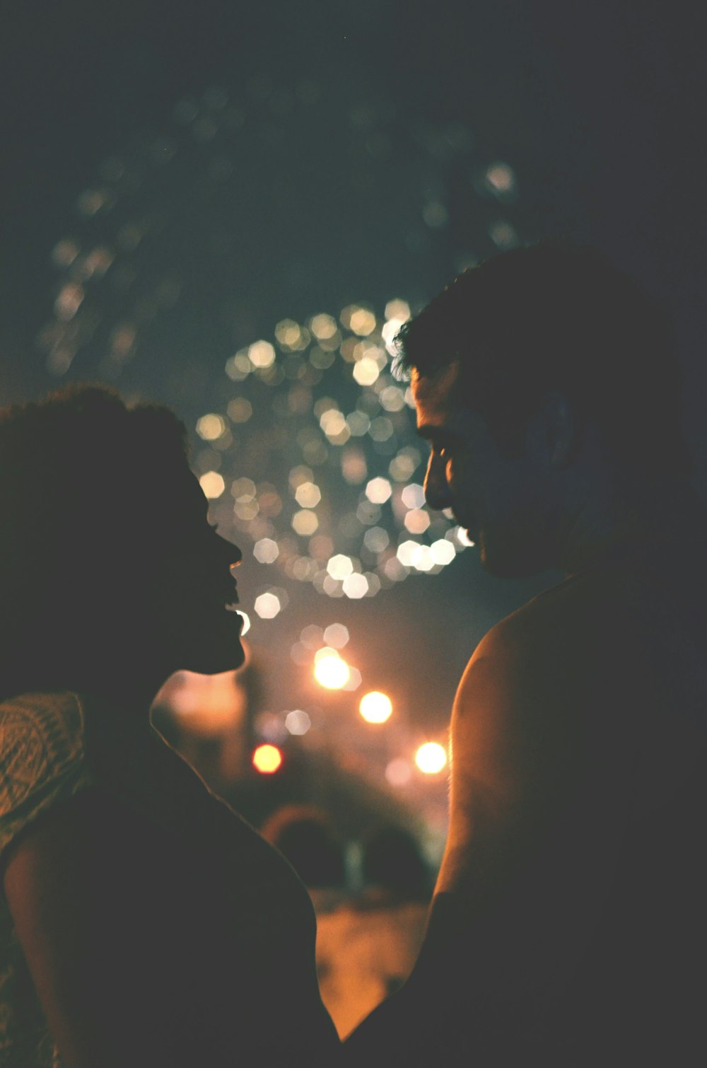 couple standing face to face at night with fireworks display