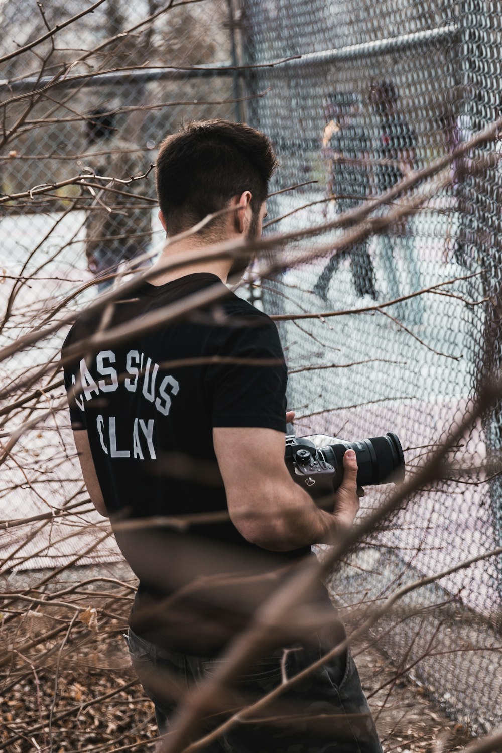 man holding camera standing near fence