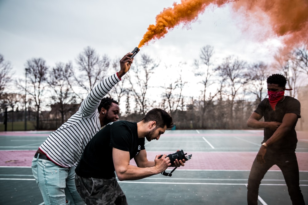 man holding can with orange smoke standing beside man holding camera