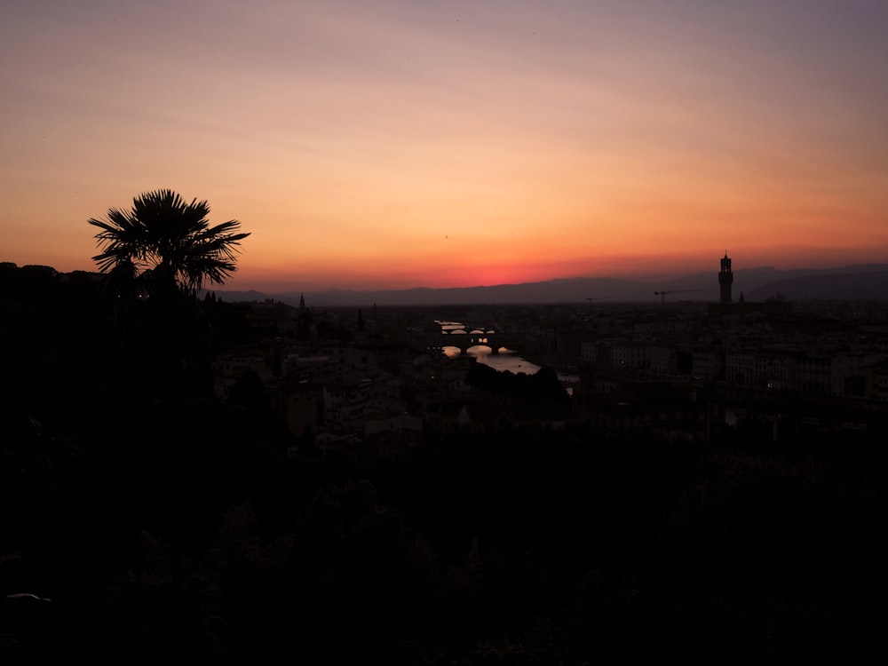 the sun is setting over a city with palm trees