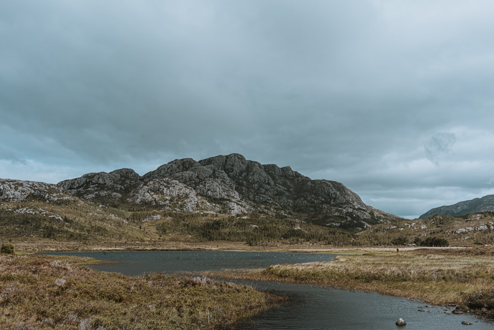 lake near mountain under gray skies