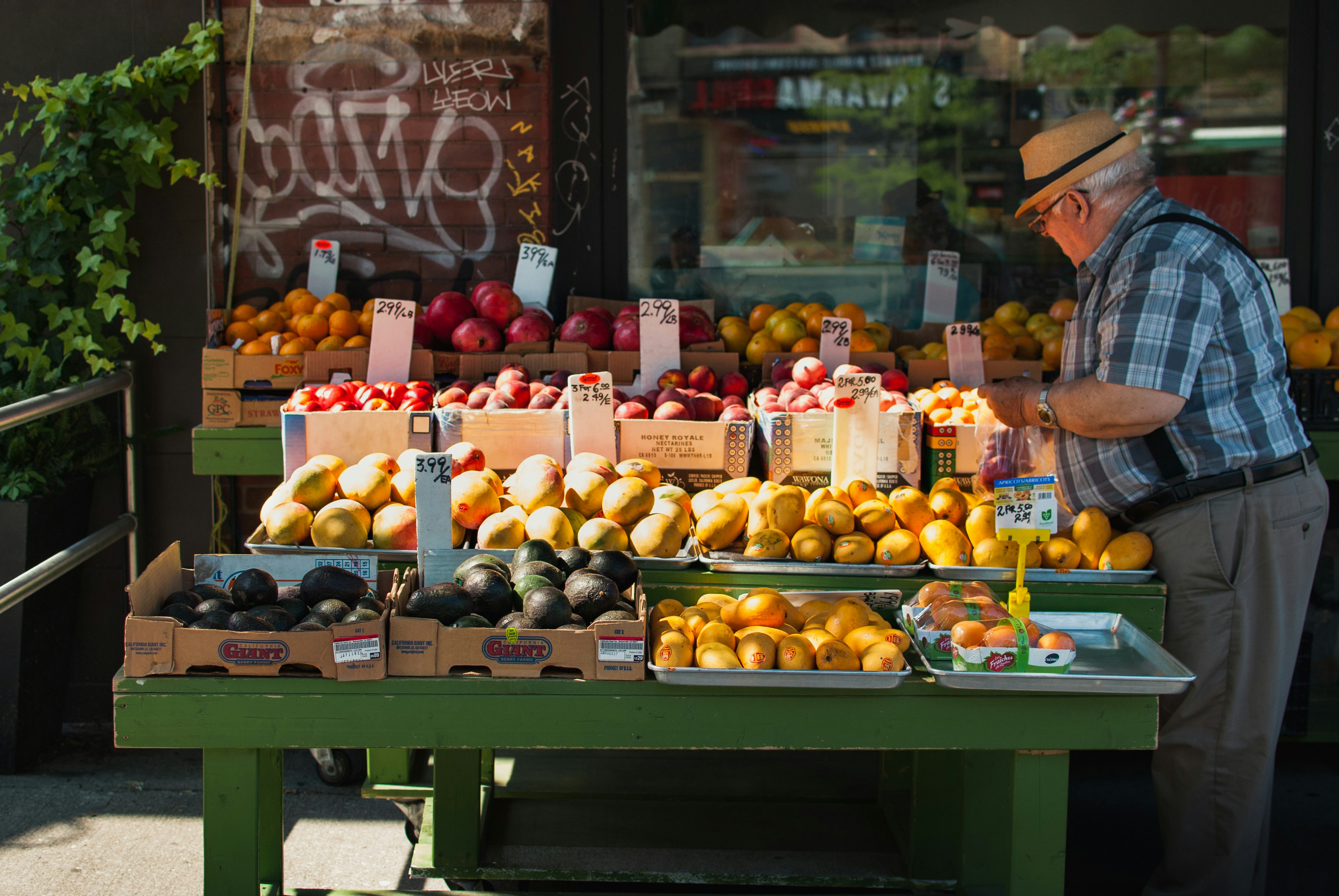 man picking fruit from a fruit stand