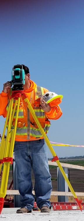 man standing and using measuring level on road