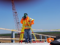 man standing and using measuring level on road