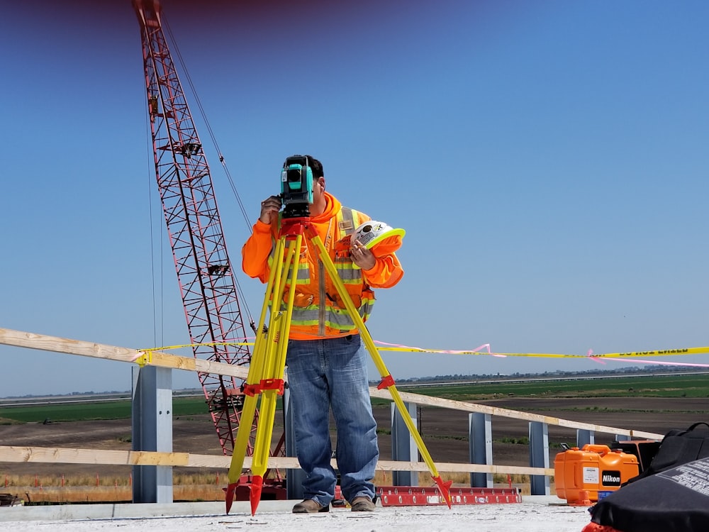 man standing and using measuring level on road