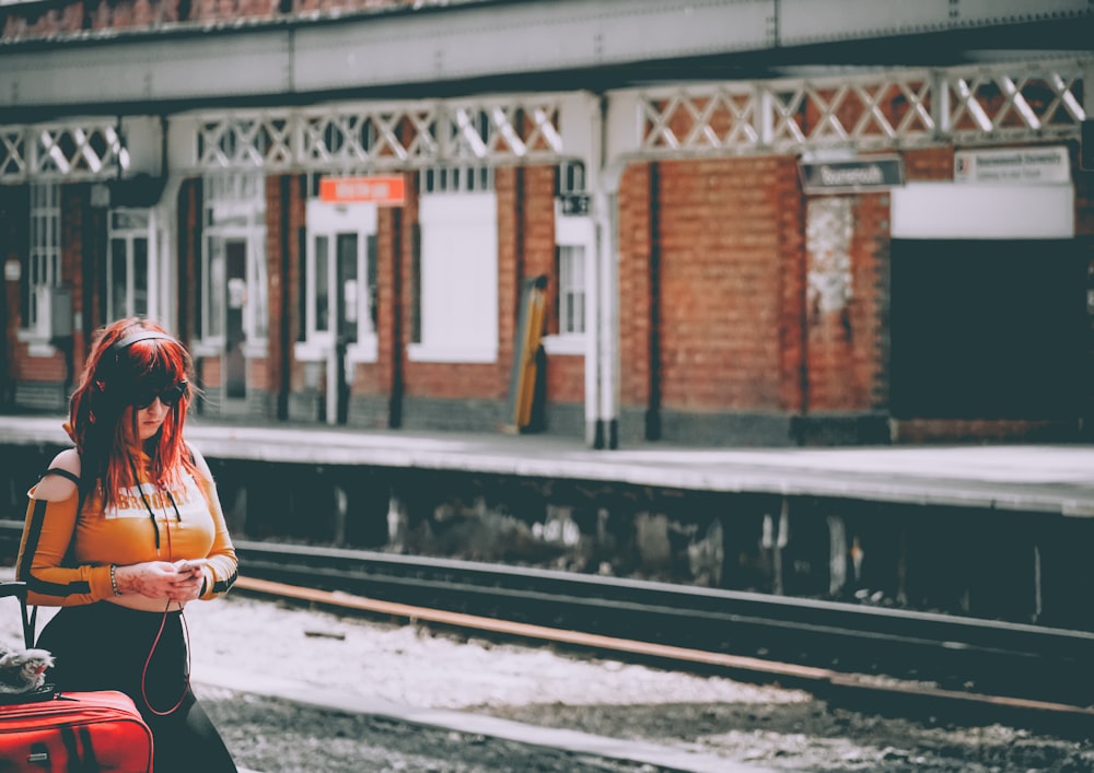 woman holding bag standing at train station