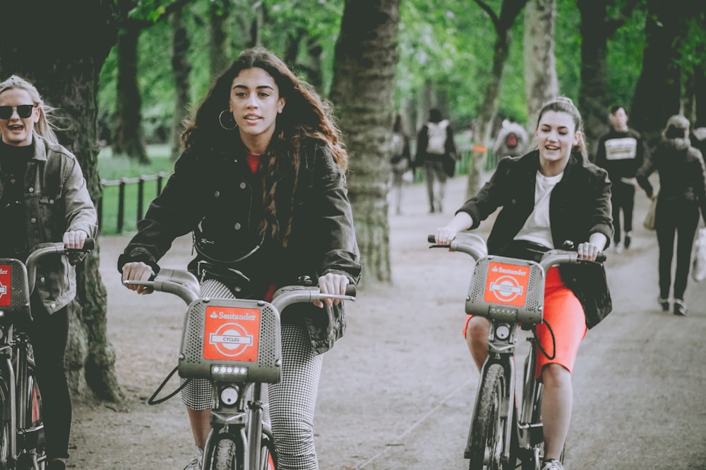 three women riding bicycles on parked