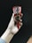 A hand holding a Kit Kat chocolate cone with a red wrapper. The product features a design showing pieces of chocolate on it.