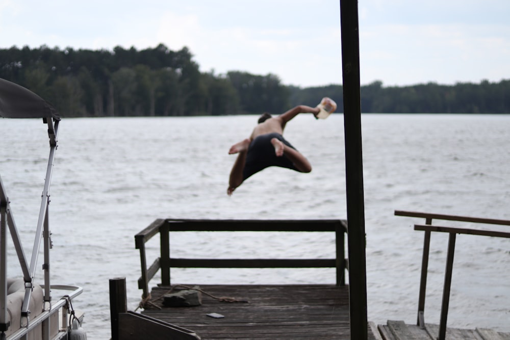 a person jumping off a dock into a body of water