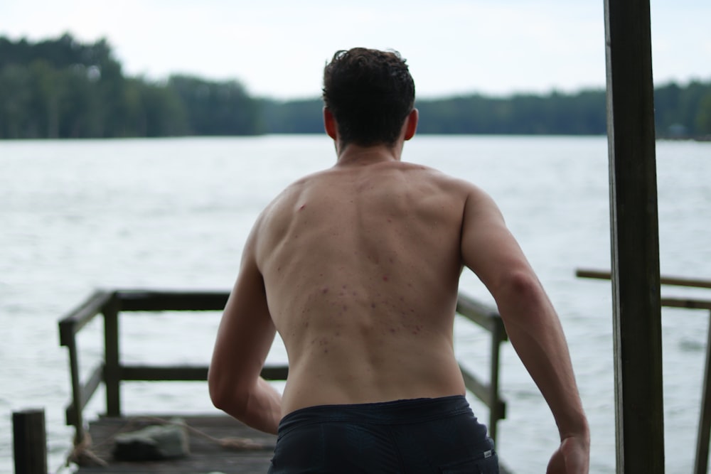 a man standing on a dock next to a body of water